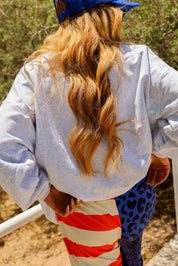 Person wearing a blue trucker hat and colorful pants with a neutral background