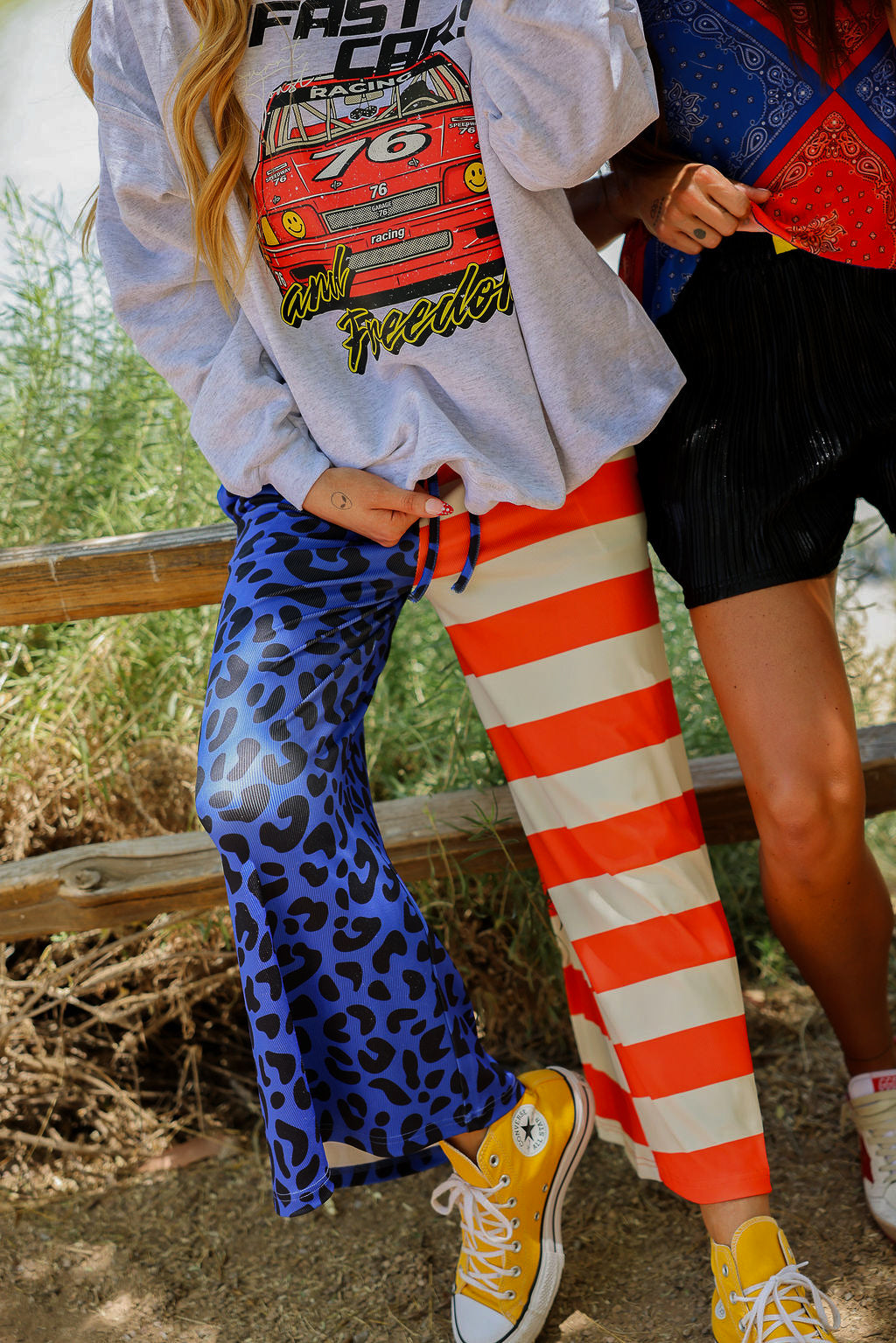 Two people wearing colorful patriotic outfits with graphic designs, standing outdoors, close up frontal view