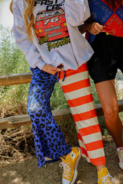 Two people wearing colorful patriotic outfits with graphic designs, standing outdoors, close up frontal view