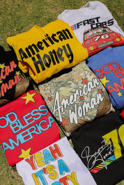 Collection of colorful t-shirts with various designs on a grassy background