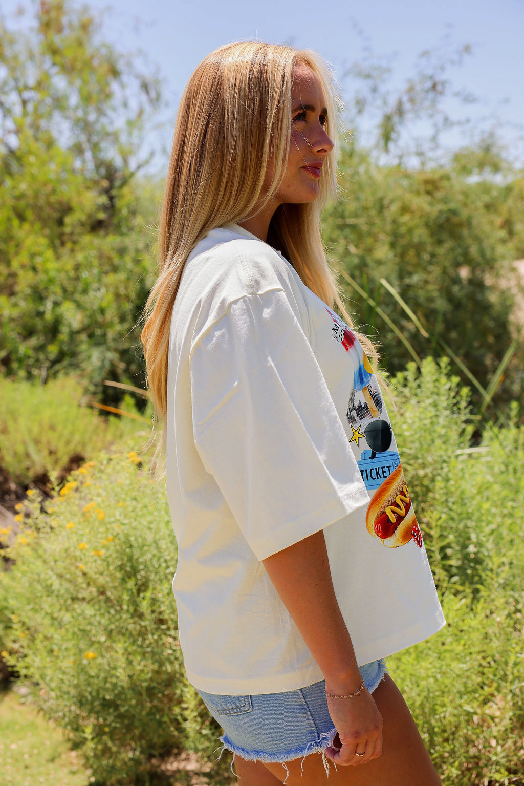 Woman wearing a white t-shirt with colorful graphics outdoors, side view