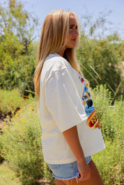 Woman wearing a white t-shirt with colorful graphics outdoors, side view