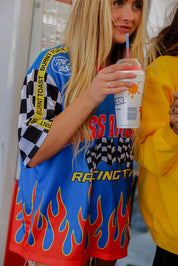 Person wearing a colorful racing-themed outfit holding a drink with a straw.