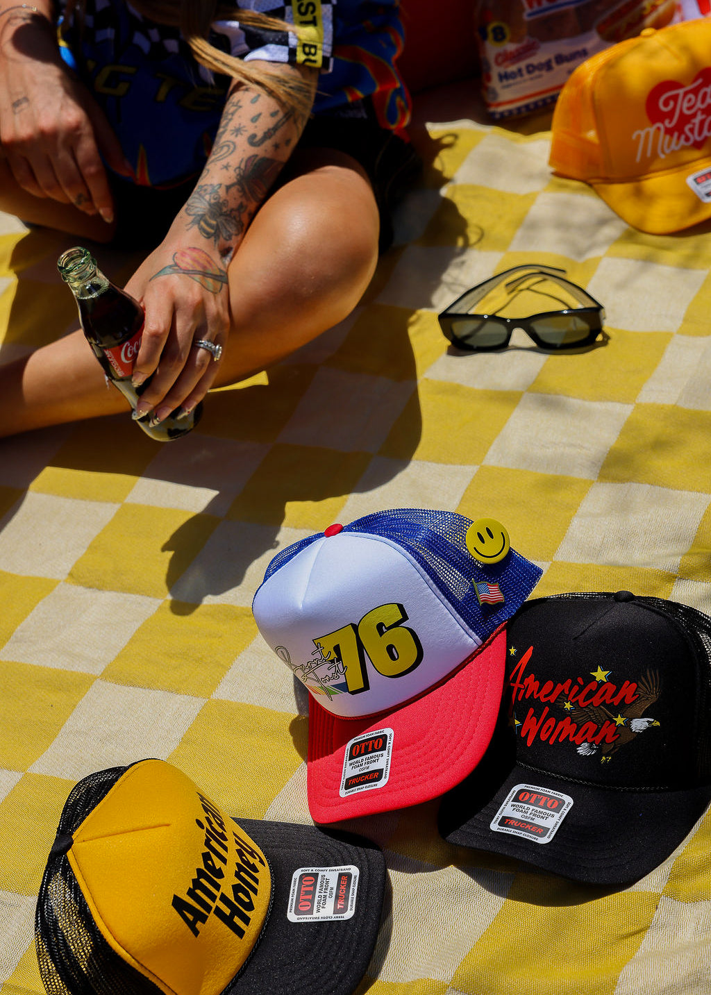 Colorful trucker hats with various designs on a yellow checkered blanket.