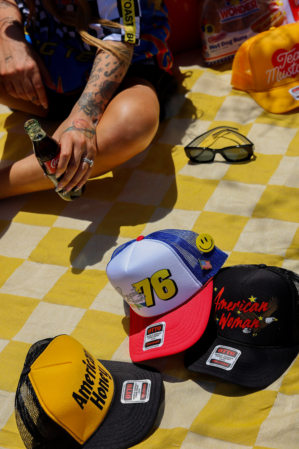 Colorful trucker hats with various designs on a yellow checkered blanket.