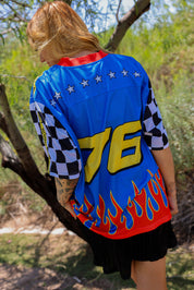 Person wearing a blue colorful racing jersey with number 76 in an outdoor setting, back view