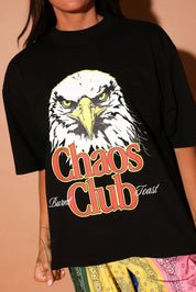 Black t-shirt with an eagle graphic and 'Chaos Club' text on a brown background, close up frontal view