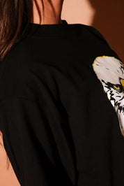 Black shirt with an eagle design on a brown background, side view