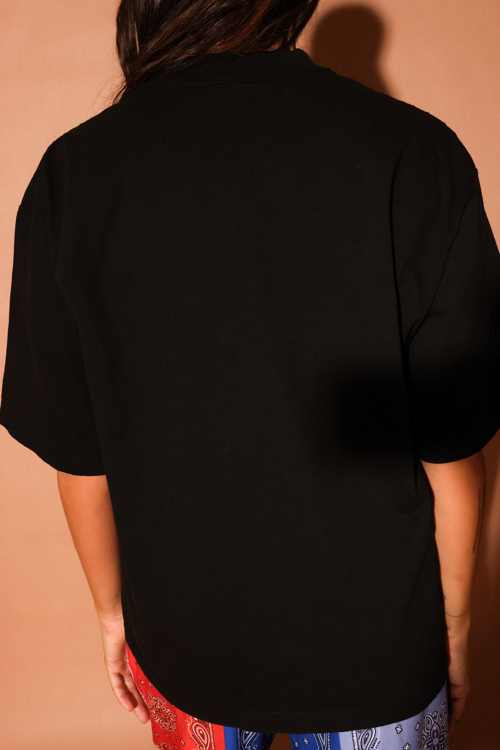 Person wearing a black shirt with a brown background, back view