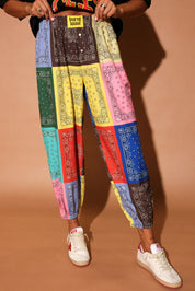 Colorful bandana print pants worn by a person on a brown background, close up view