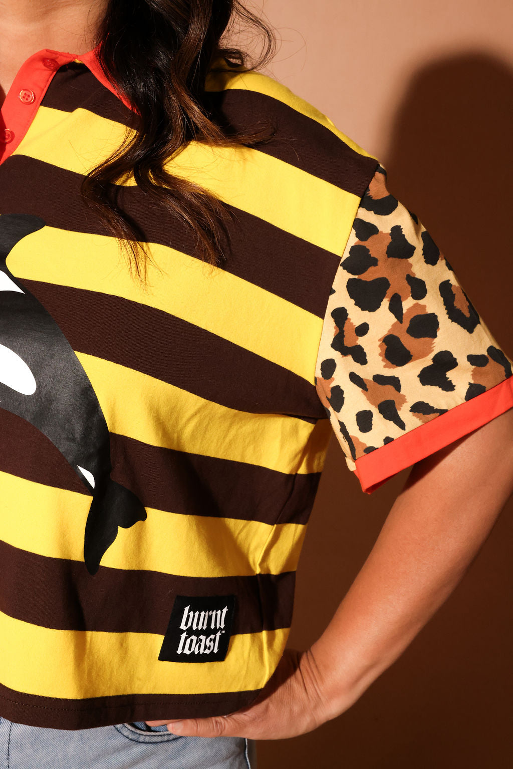 Person wearing a striped shirt with a leopard print sleeve and 'burnt toast' label, close up view