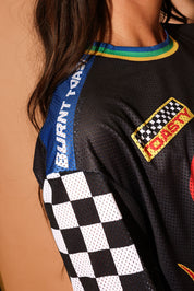 Close-up of a black sports jersey with colorful accents and brand logos on a brown background, focus on neckline
