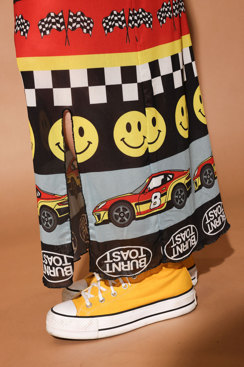 Skirt with race car and smiley face pattern on a brown background, close up lower half of body view
