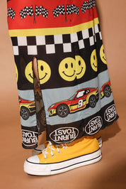 Skirt with race car and smiley face pattern on a brown background, close up lower half of body view