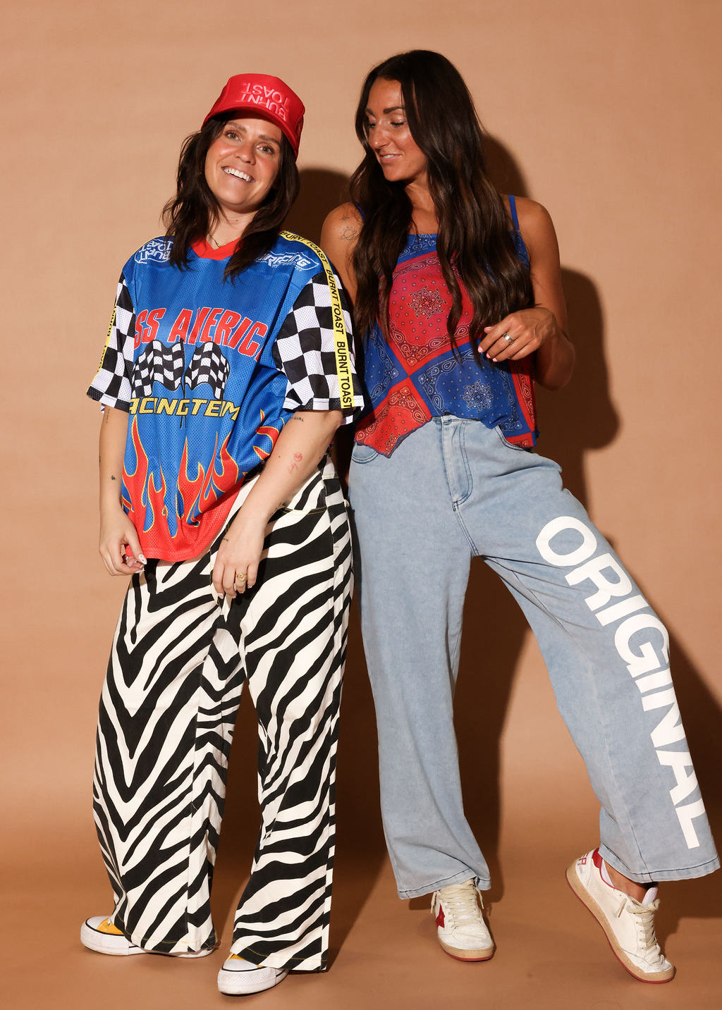 Two people posing together, wearing red white and blue outfits, against a brown background