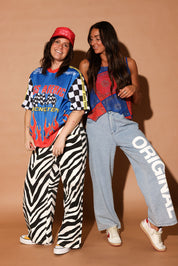 Two people posing together, wearing red white and blue outfits, against a brown background