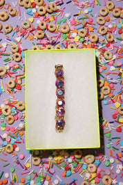 Colorful bracelet on a yellow card with cereal and sprinkles in the background