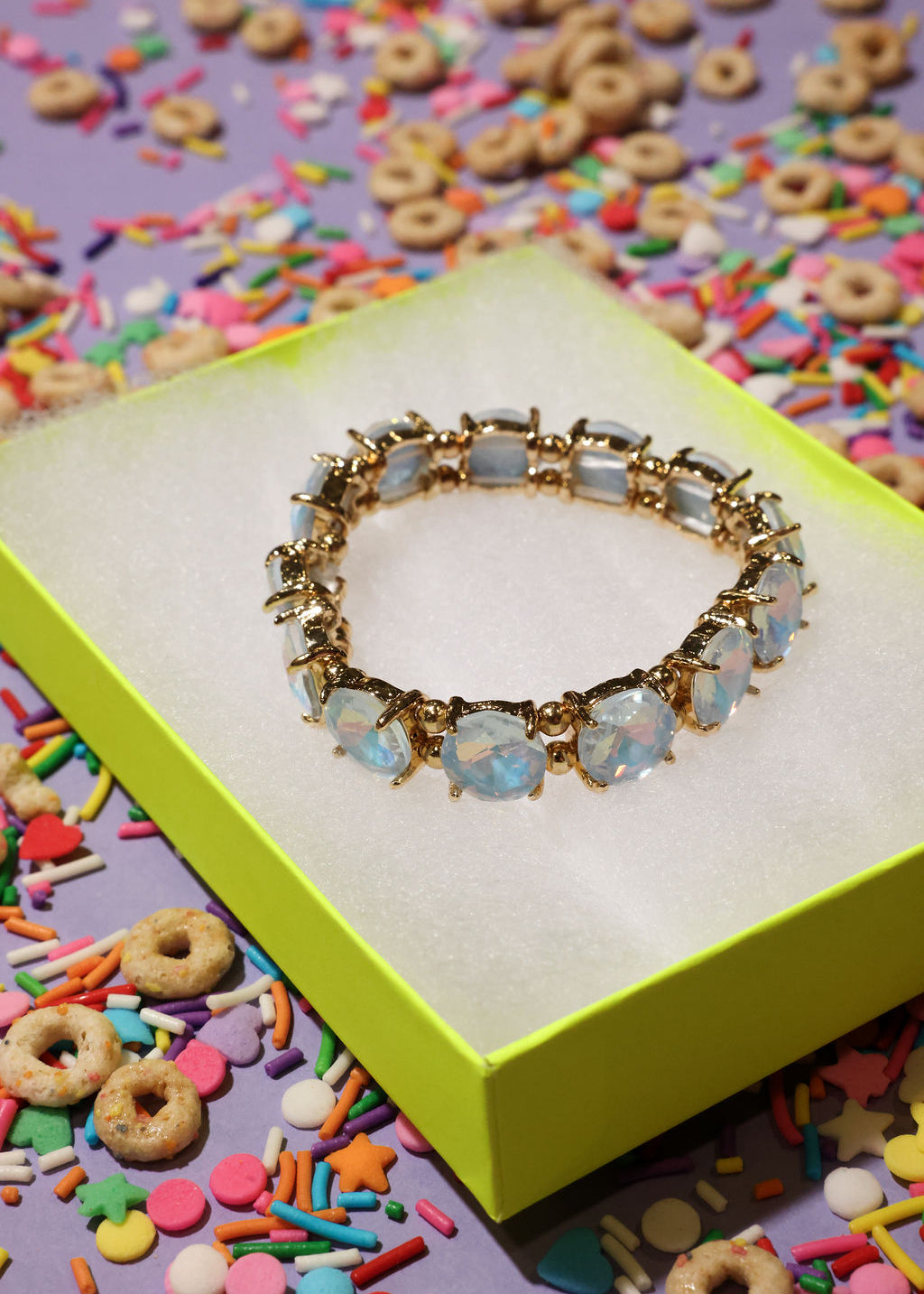 Gold bracelet with opal stones on a colorful sprinkles background