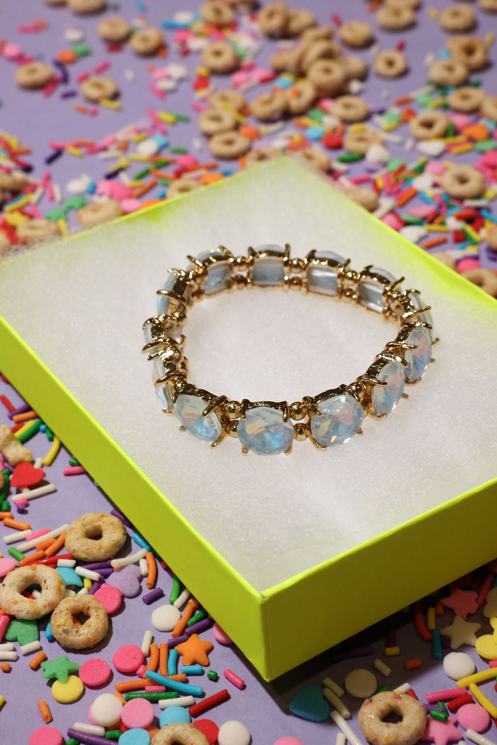Gold bracelet with opal stones on a colorful sprinkles background