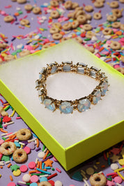 Gold bracelet with opal stones on a colorful sprinkles background