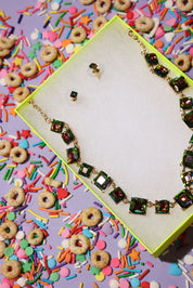 Necklace with colorful gemstones on a box surrounded by cereal and sprinkles