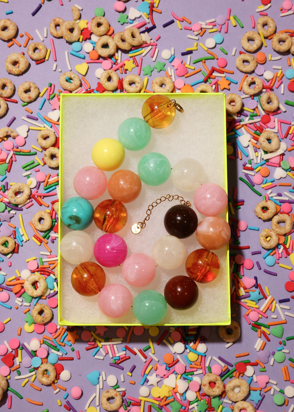 Colorful bead necklace on a yellow card with a colorful background of sprinkles and cereal
