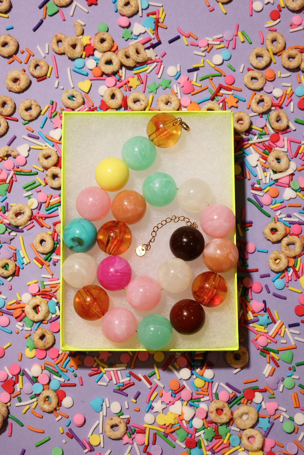 Colorful bead necklace on a yellow card with a colorful background of sprinkles and cereal