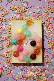 Colorful bead necklace on a yellow card with a colorful background of sprinkles and cereal