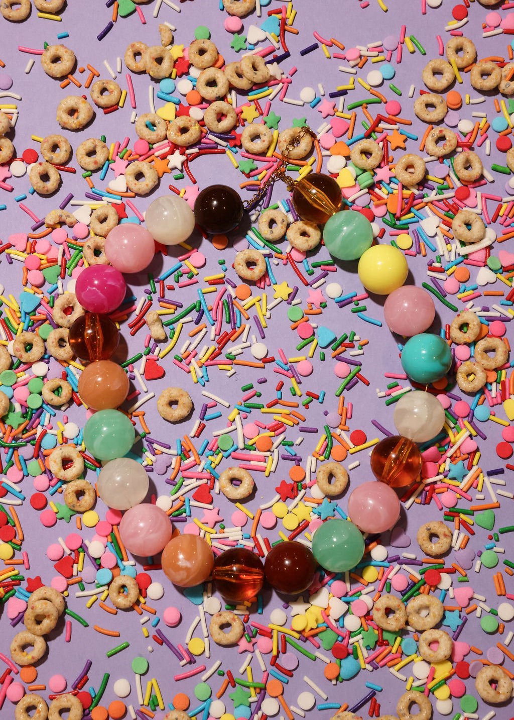 Colorful beads and cereal loops on a purple background with sprinkles