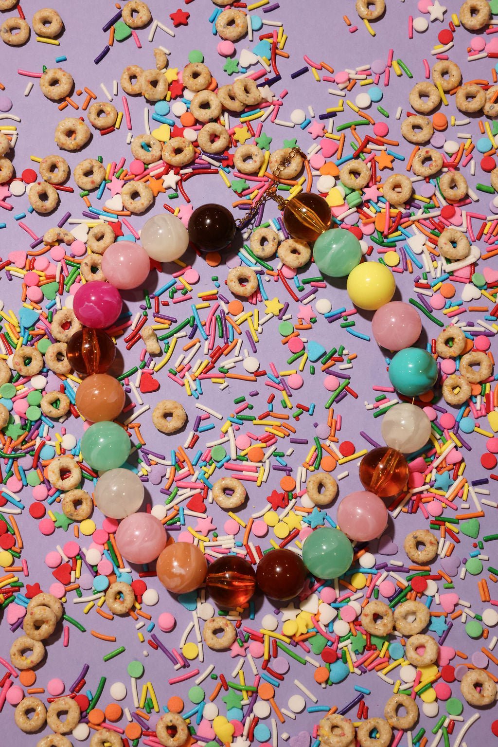 Colorful beads and cereal loops on a purple background with sprinkles