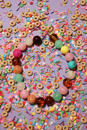 Colorful beads and cereal loops on a purple background with sprinkles