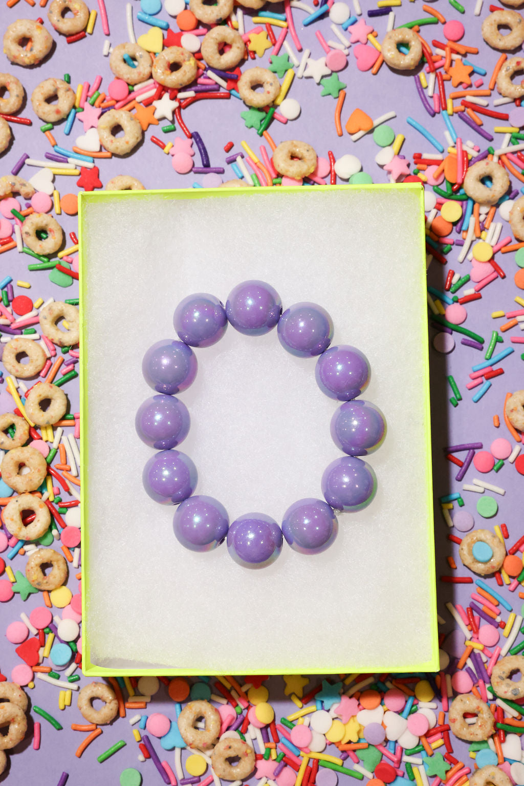 Purple beaded bracelet on a white card with colorful cereal and sprinkles in the background