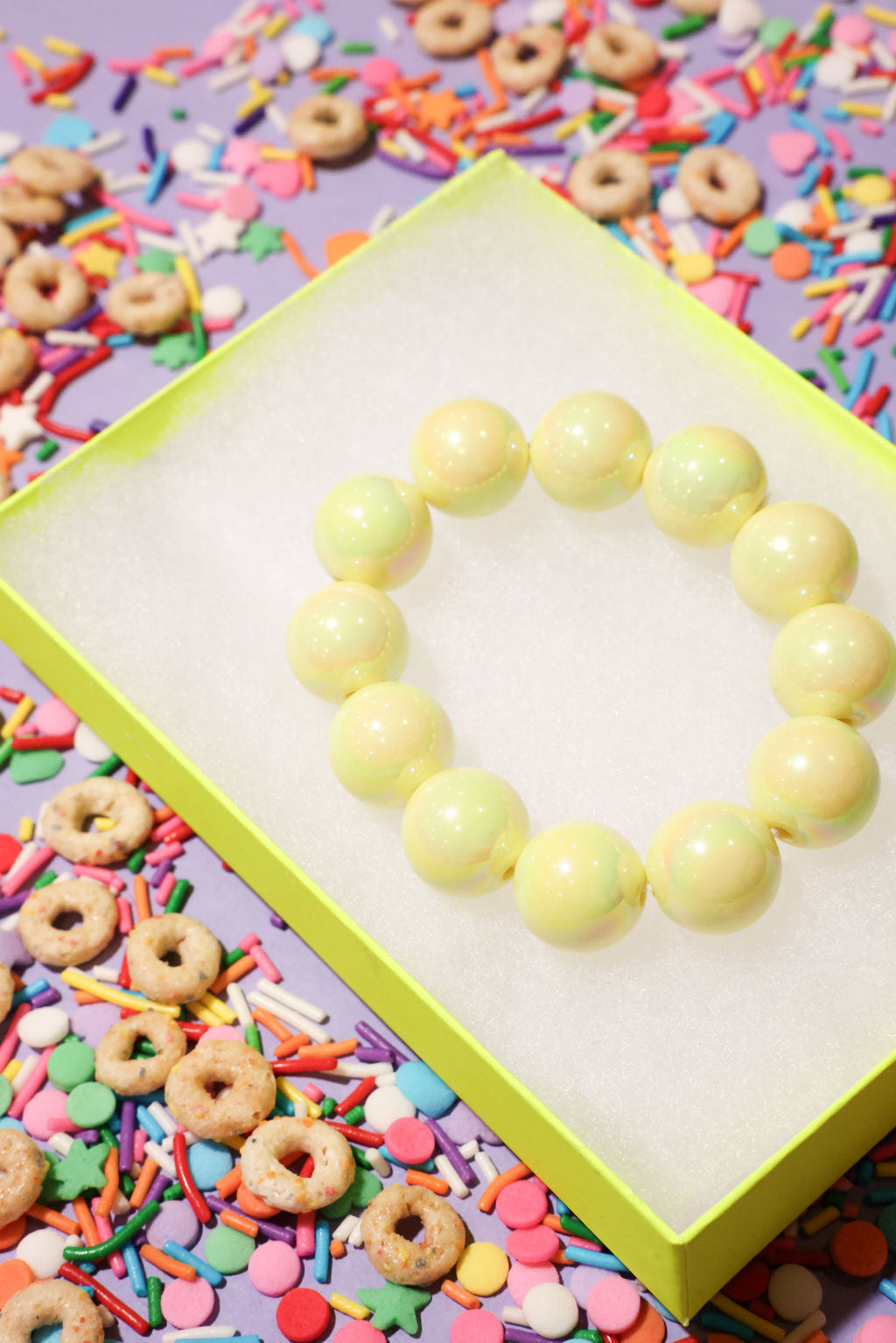 Yellow beaded heart on a colorful background with sprinkles and cereal