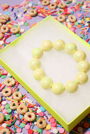 Yellow beaded heart on a colorful background with sprinkles and cereal
