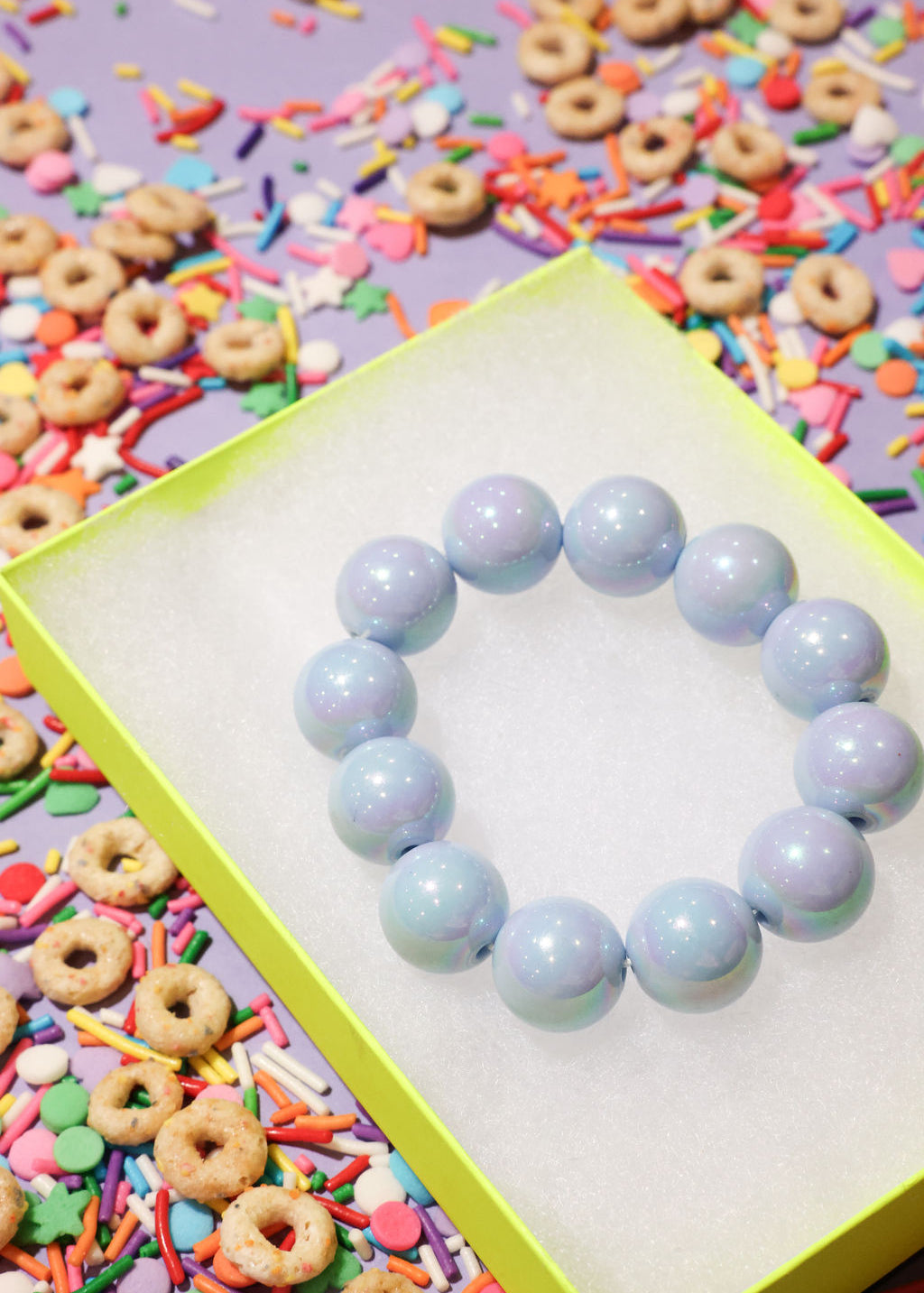Light blue beaded bracelet on a colorful background with cereal and sprinkles