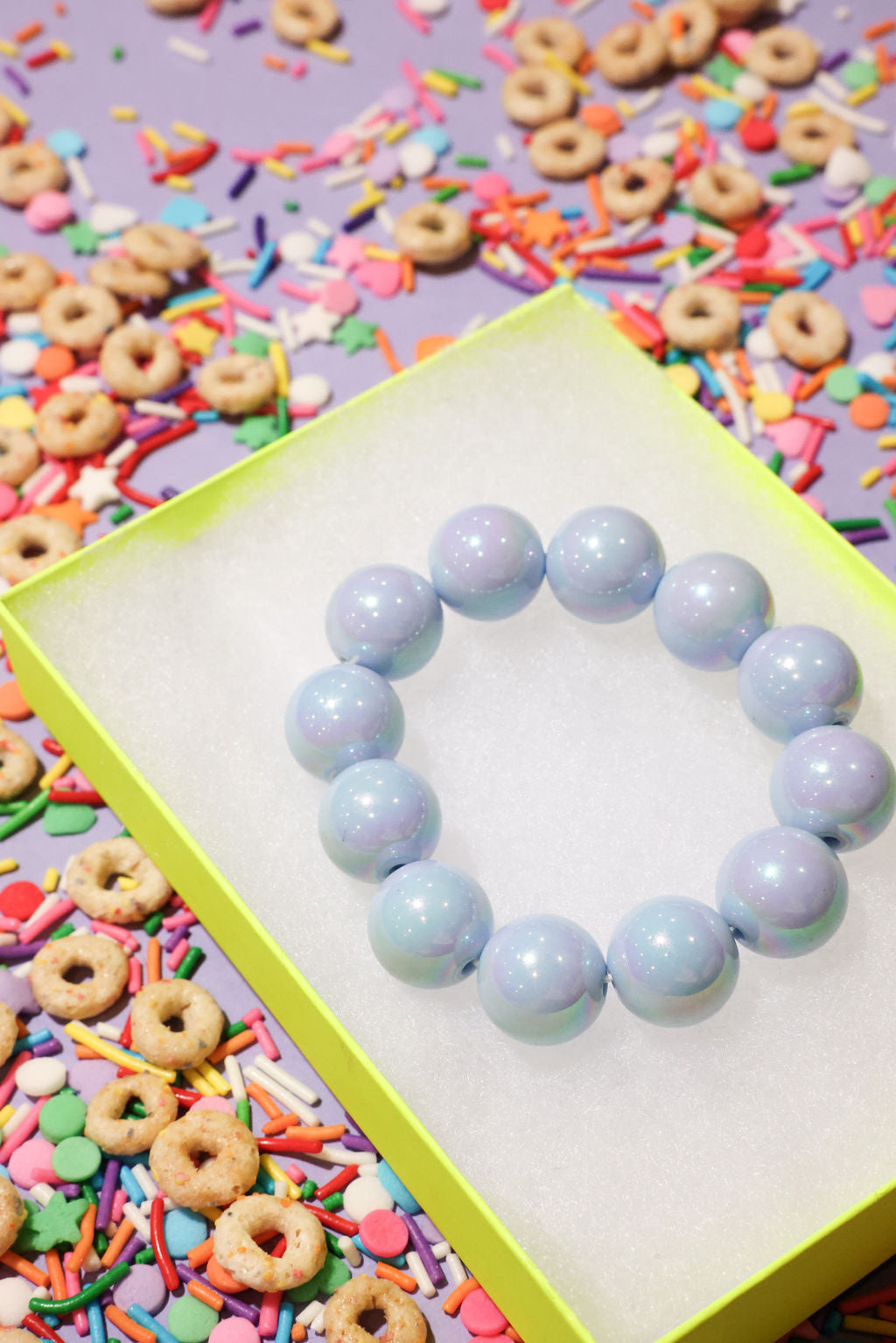 Light blue beaded bracelet on a colorful background with cereal and sprinkles