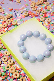 Light blue beaded bracelet on a colorful background with cereal and sprinkles