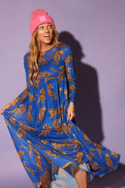Model wearing a long sleeve blue mesh dress with tiger patterns and a pink beanie, against a purple background, close up frontal view