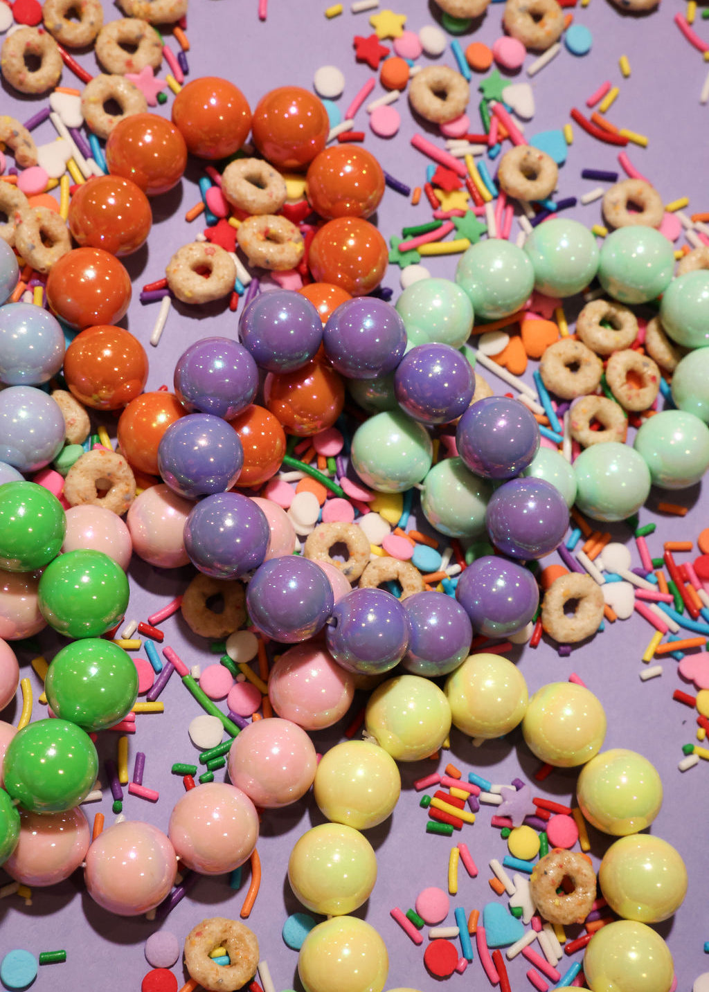 Colorful beaded bracelets and sprinkles on a purple background