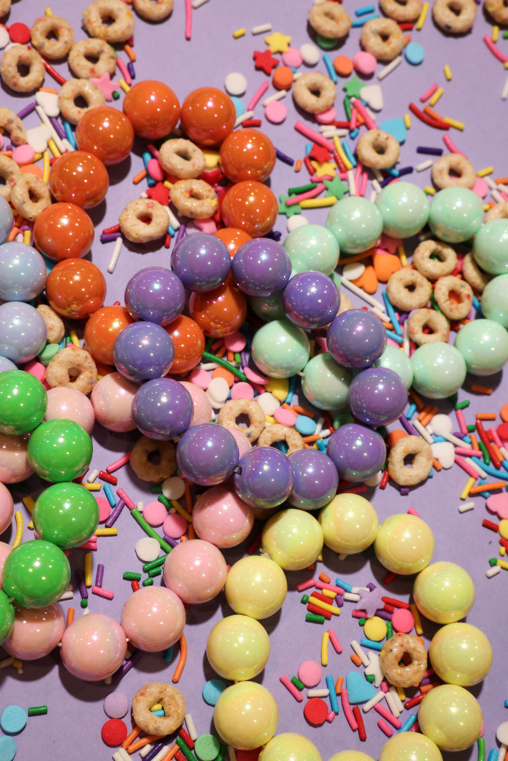 Colorful beaded bracelets and sprinkles on a purple background
