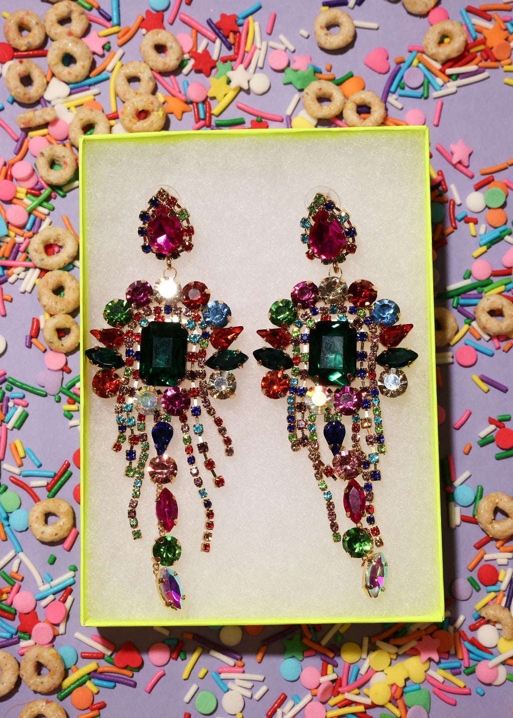 Colorful rhinestone earrings on a yellow card with a colorful background of cereal and sprinkles