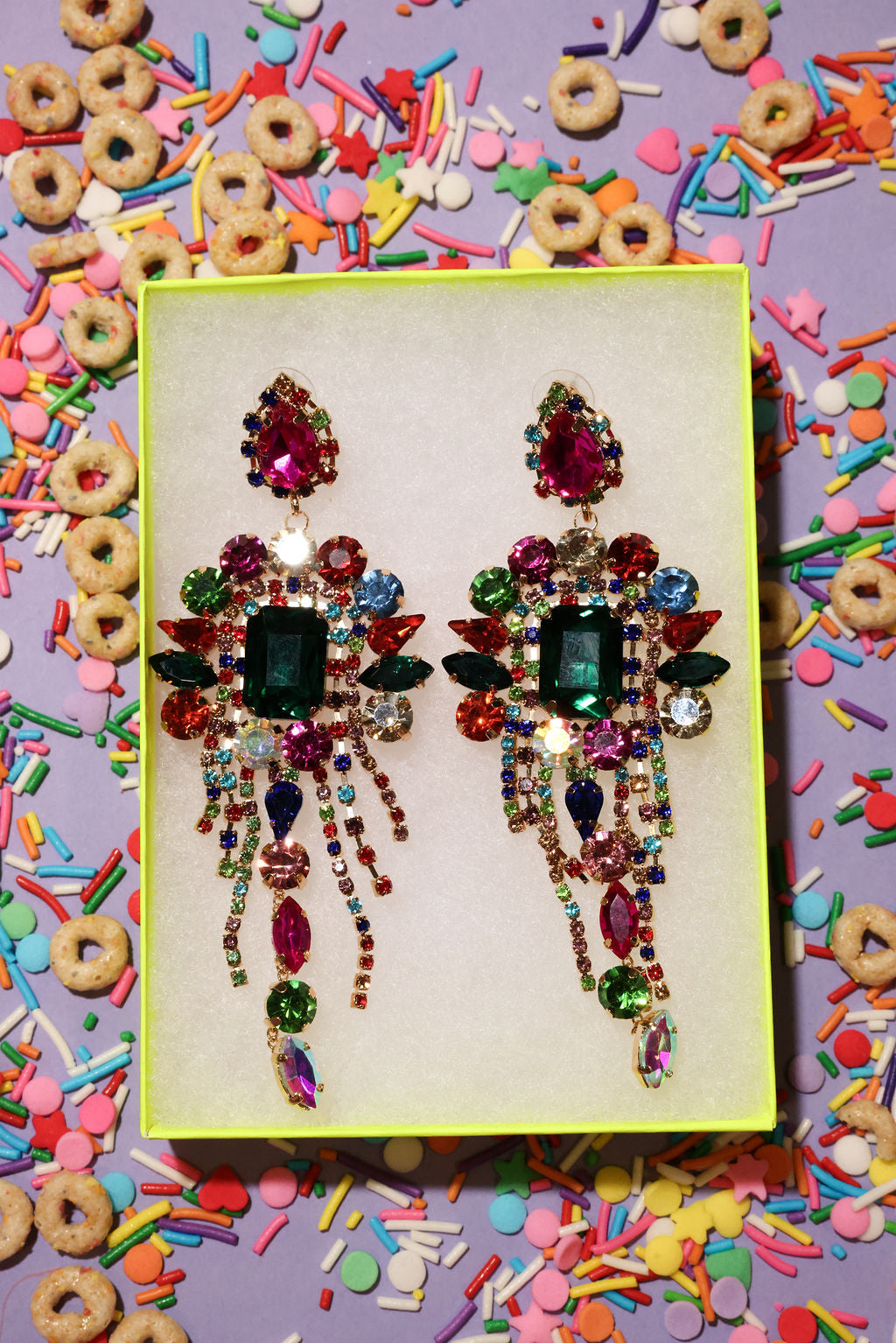 Colorful rhinestone earrings on a yellow card with a colorful background of cereal and sprinkles
