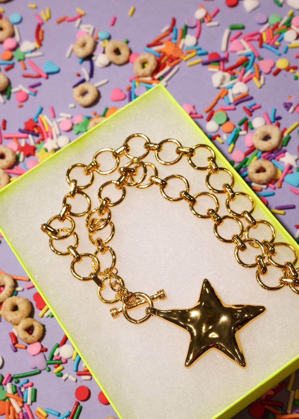 Gold chain necklace with a star charm on a colorful background