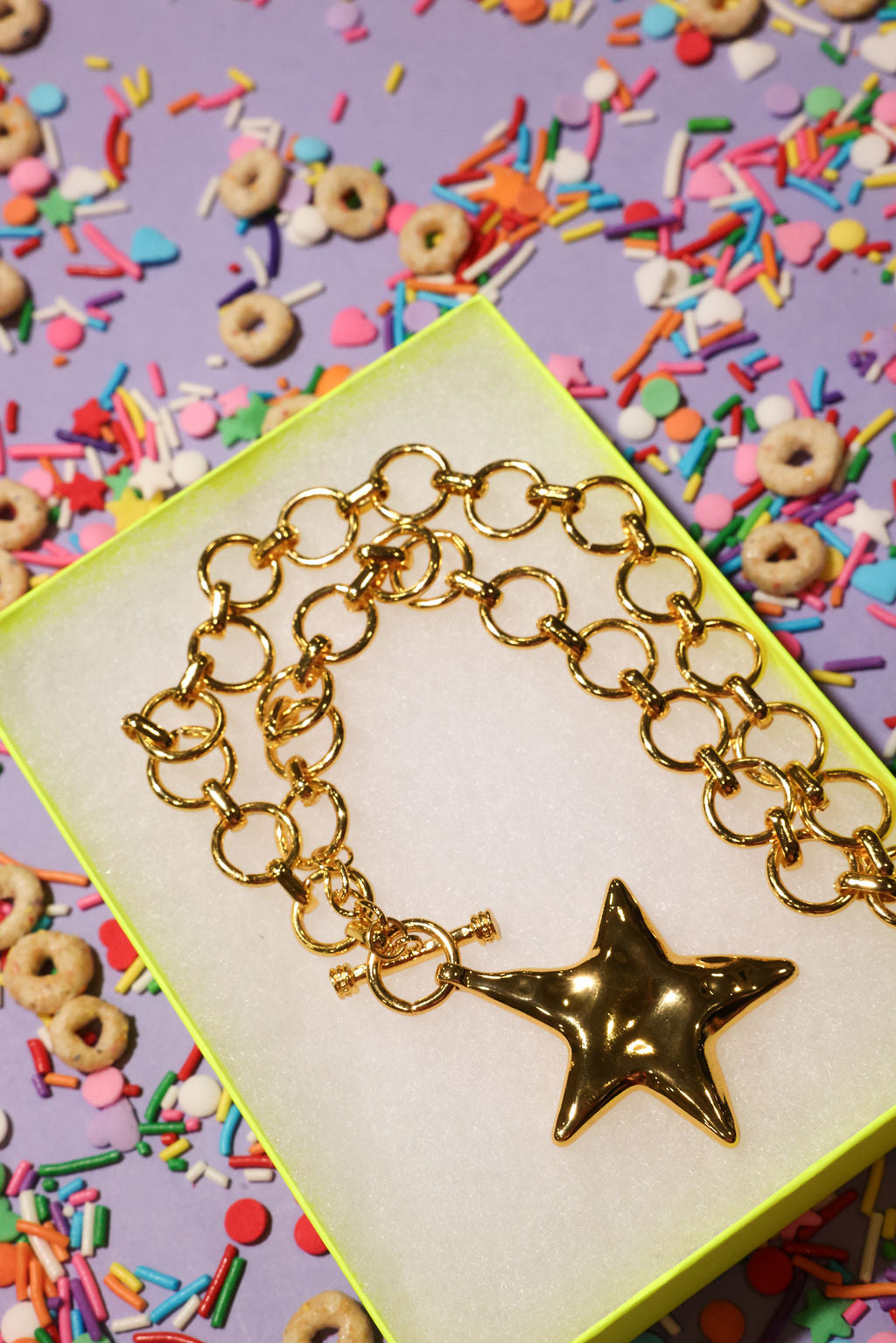 Gold chain necklace with a star charm on a colorful background