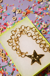 Gold chain necklace with a star charm on a colorful background