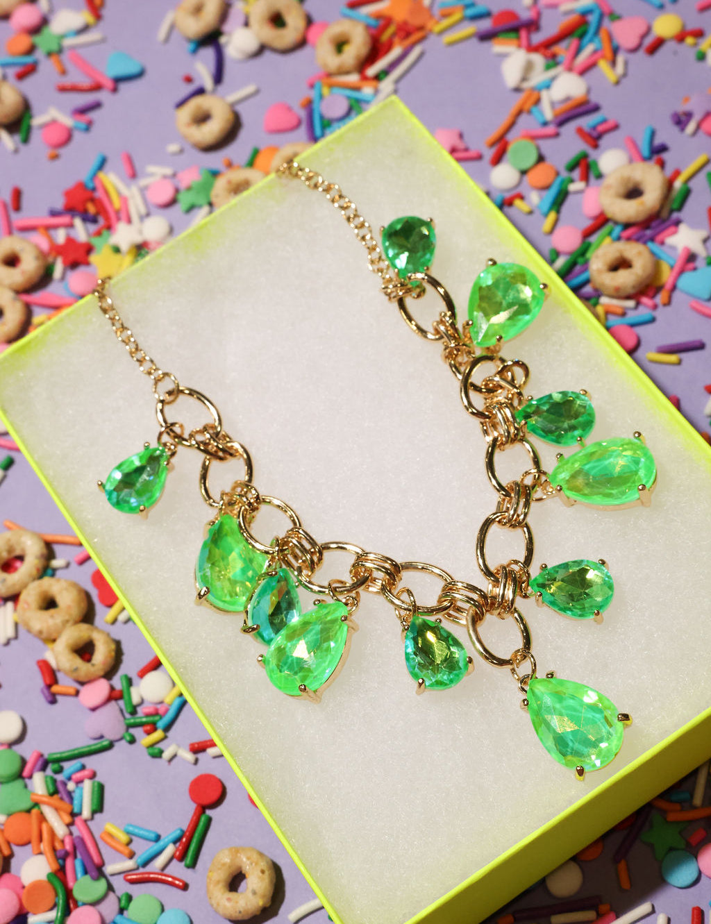 Necklace with green teardrop pendants on a colorful background