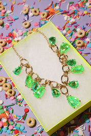 Necklace with green teardrop pendants on a colorful background