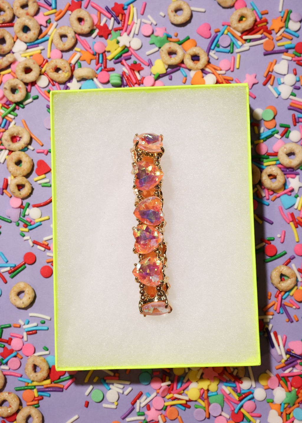 Colorful bracelet on a white card with a vibrant, multicolored background of donuts and sprinkles.
