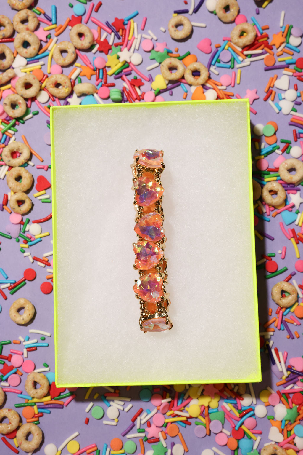 Colorful bracelet on a white card with a vibrant, multicolored background of donuts and sprinkles.