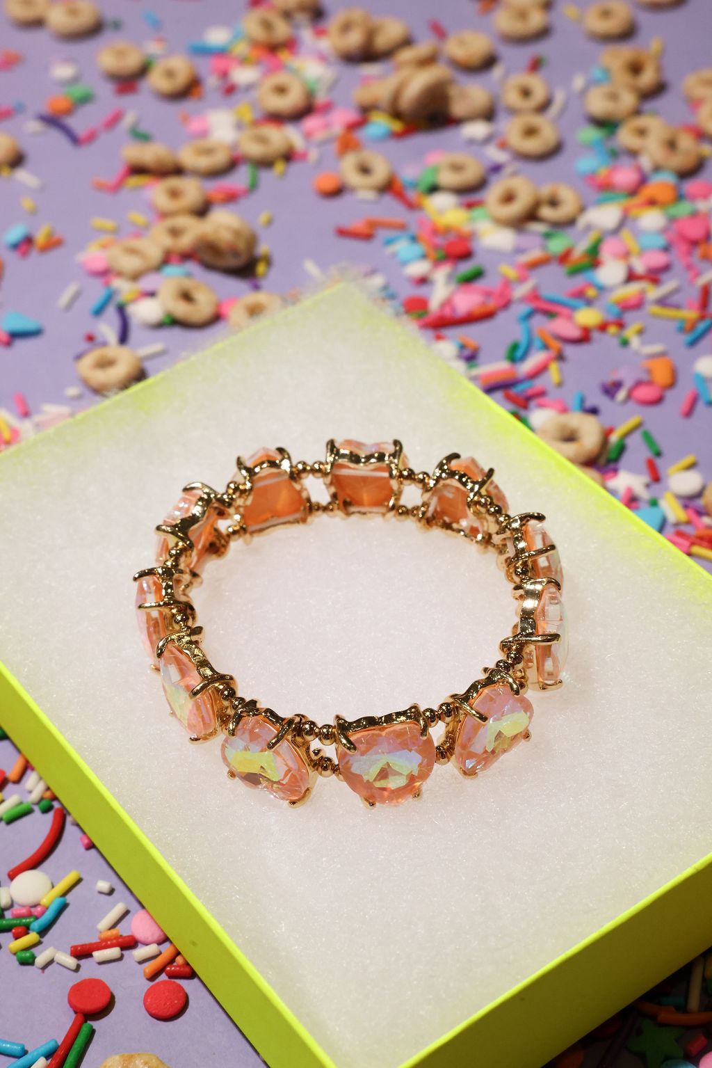 Bracelet with colorful charms on a box surrounded by cereal and sprinkles